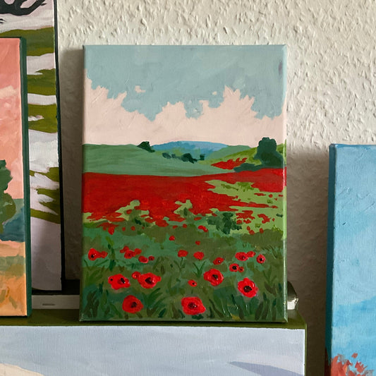 Small painting of a field with red flowers on a shelf